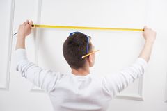 young-handsome-worker-measuring-tape-caucasian-protective-glasses-pencil-using-view-behind-white-wall-background-42371443
